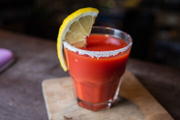 Tomato juice with lemon on a wooden stand in a restaurant.