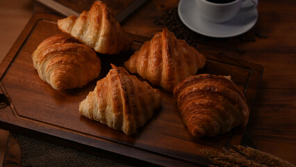 Delicious fresh croissants and coffee cup on wooden board