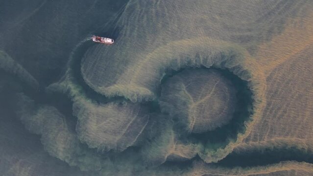 A bird's-eye view of a researching ship in a cloudy sea.