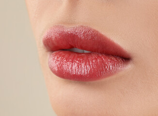 Woman with beautiful perfect lips after permanent makeup procedure on beige background, closeup