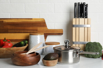 Different cooking utensils and fresh vegetables on countertop in kitchen