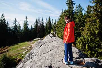 Naklejka na ściany i meble Boy on top of mountain. Children hiking on beautiful day in mountains, resting on rock and admire amazing view peaks. Active family vacation leisure with kids.Outdoor fun and healthy activity.
