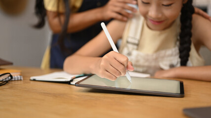 Focused asian girl using digital tablet, doing homework, studying online on web virtual class