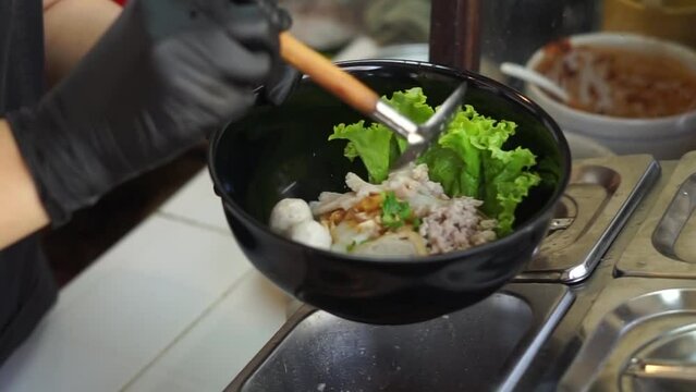 Stainless steel strainer over the hot noodle 
pot with white smoke from boiling steam in a
kitchen. Thailand street food