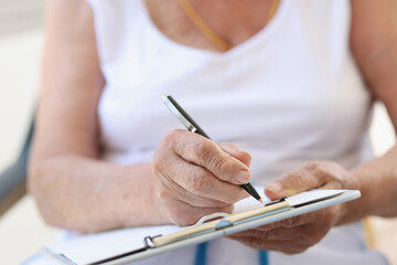 Hands of old woman with sheet for writing text