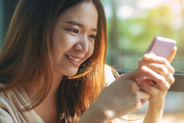 Attractive Asian woman using smartphone at workplace, relaxing, happy and smile.	 Selected focus