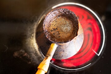 invigorating coffee in an old Turkish pot on a hot stove on a bright spring morning is prepared and infused
