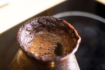 invigorating coffee in an old turk on the stove on a bright spring morning lets off steam