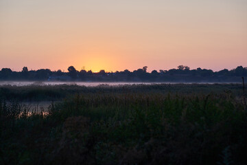 Photo of fog on the background of a rural river at sunset