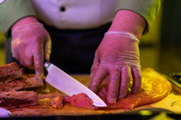 Chef in hotel or restaurant kitchen cooking, only hands. Prepared salmon steak with dill decoration.
