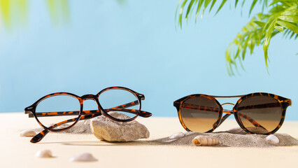 Trendy sunglasses and eyeglasses on a beach with palm leaves. Close up. Sunglasses and spectacles...