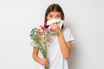 Pretty girl allergic to bouquet of wild flowers in her hands, blowing nose in handkerchief