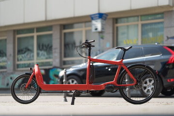 red cargo bike in front of a passing car in an urban situation in germany