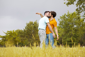 Gay couple in the park. Young man hugging and kissing his boyfriend. High quality photo