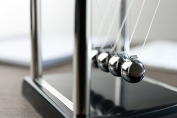 Newton's cradle on wooden table, closeup. Physics law of energy conservation