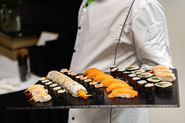 Waiter carrying plates with sushi on some festive event, party or wedding reception
