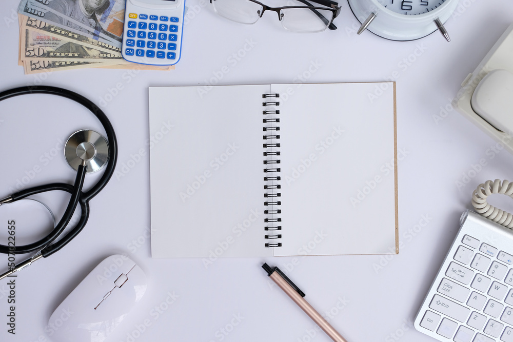 Poster blank notepad with a pen rests on an office desk table, surrounded by computer equipment and various