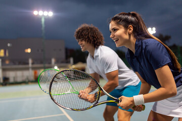 Tennis sport people concept. Mixed doubles player hitting tennis ball with partner standing near net