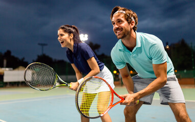 Beautiful young people are playing tennis as a team on tennis court outdoors. People sport concept