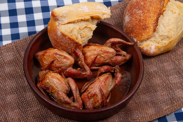 Four roasted quails and two chunk of white bread. Rustic style