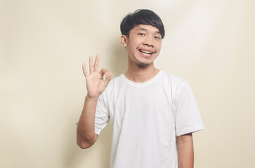 portrait of an asian man doing an okay gesture on an isolated background