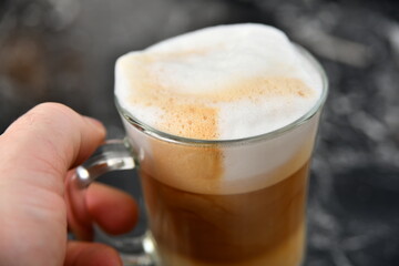 A man holds a cup of espresso coffee in his hand.