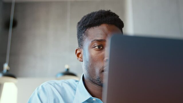 Portrait of young african american man in living room using laptop close-up