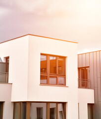 The apartment building at sunset. Condominium construction in the evening. Strong sunlight falls on the low-rise modern residential building