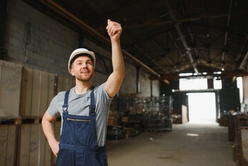 Portrait of happy male worker in warehouse standing between shelves.