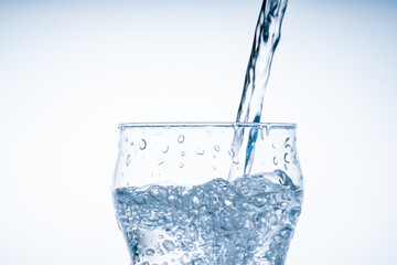 Ice cube fell into the glass of water. Water splashed from the clear glass. Fresh concept