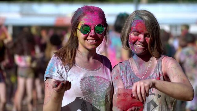 Happy girls holding and spraying colorful paints at Holi festival.