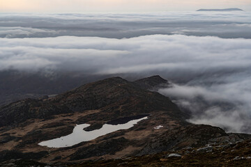 A mountain lake surrounded by low cloud and a distant island