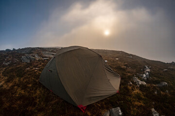 A wild camping tent in misty mountain weather 