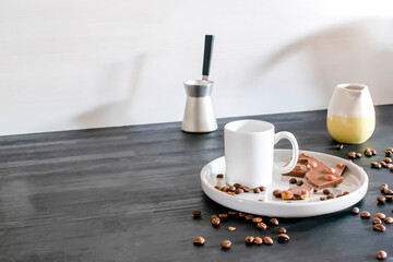 Fototapeta na wymiar white espresso cup, mug, chocolate, coffee beans on plate kitchen table, utensils dishware, coffee pot on black wooden shelf. Early morning french home hot beverage breakfast, copy space