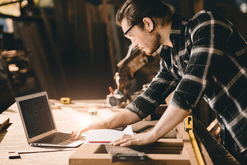 Plakat builder wood worker wooden furniture maker using laptop computer to design project