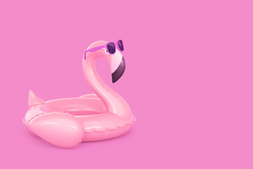 Inflatable flamingo in sunglasses on pink background