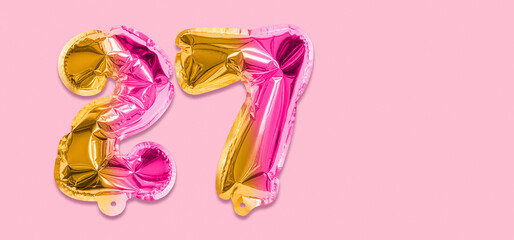 Rainbow foil balloon number, digit twenty seven on a pink background. Birthday greeting card with inscription 27. Top view. Numerical digit. Celebration event, template. Banner