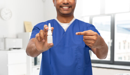 healthcare, profession and medicine concept - close up of happy smiling doctor or male nurse in blue uniform with nasal spray over medical office at hospital background