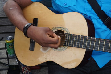 Mann sitzt auf Bank und spielt Gitarre 