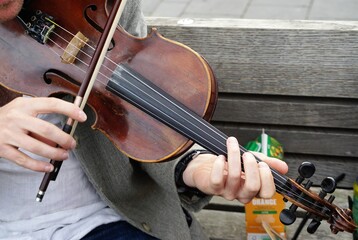 Oberkörper von Musiker beim Geige spielen auf grauer Holzbank in Stadt 