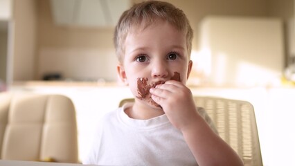 baby boy eat chocolate. dirty little baby kids in the kitchen eating chocolate in the morning....