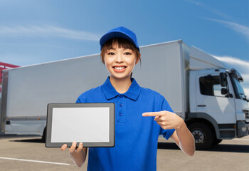 logistics, shipping and job concept - happy smiling delivery woman in blue uniform with tablet pc computer over truck background