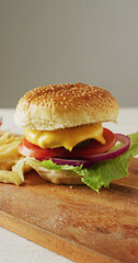 Vertical image of fresh homemade hamburger with salad on wooden chopping board