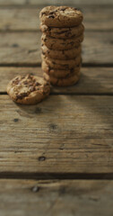 Vertical image of stack of chocolate chip cookies on wooden background