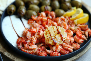 Plate with boiled shrimps with olives, lemon and sauce. Healthy snack. Italian food.