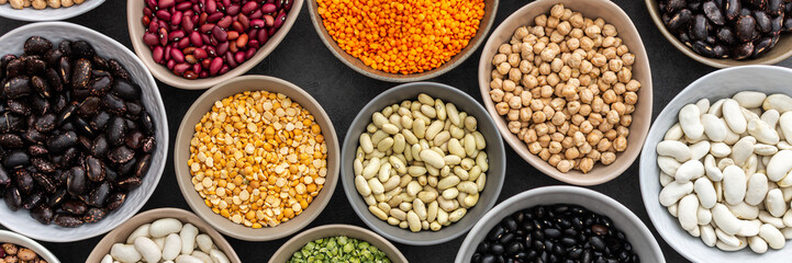 Banner of different types of legumes in bowls, green with yellow peas and mung beans, chickpeas and peanuts, colored beans and lentils, top view
