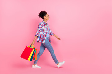 Full length body size profile side view of attractive cheerful girl going carrying bags isolated over pink pastel color background