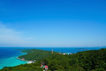 Beautiful viewpoints of Koh Larn island, bright blue skyline, deep turquoise shade of sea water, green tree mountain and cityscape around bay. Landmark and travel destination of Pattaya Thailand.
