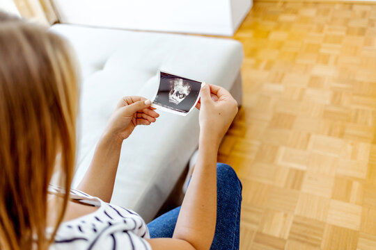 Shot of a woman holding a sonogram of her unborn baby. Happy young pregnant woman holding an ultrasound scan image. Pregnant mother is showing ultrasound of her baby.