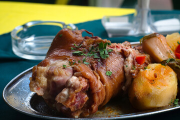 Serbian pork knuckle (svinjska kolenica) stewed under sać pot with potatoes and vegetables